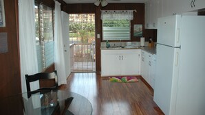 Une cuisine de taille réduite, avec des meubles de rangement en bois, un réfrigérateur blanc et un ventilateur de plafond.