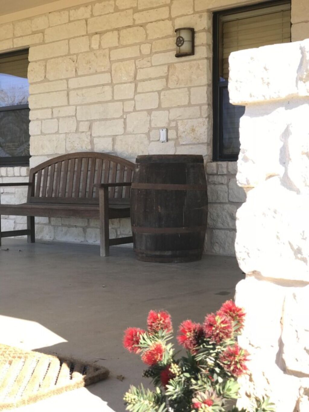 A stone building with a wooden bench and a barrel.