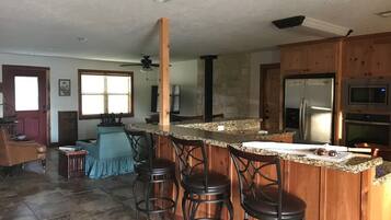 A kitchen with a granite countertop, wooden cabinets, a stainless steel refrigerator, and a microwave.