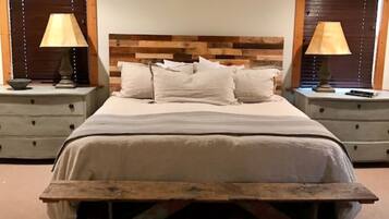 A bedroom with a wooden headboard, two bedside tables with lamps, and a large bed with pillows.