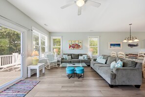 A spacious living area with a gray sofa, blue ottomans, and a dining table.