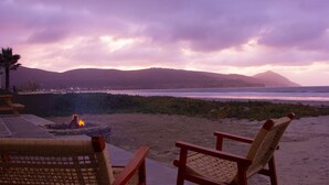 Blick auf einen Strand mit Stühlen und einer Feuerstelle.