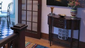 Ein Zimmer mit Holztür, einem Tisch mit Stühlen, einem Bild von einem Haus am Wasser und einer Vase mit Blumen.