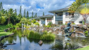 A hotel with a pond, palm trees, and a waterfall. - North Shore Beauty!  2B with Kitchen in Resort near Hanalei (Princeville)