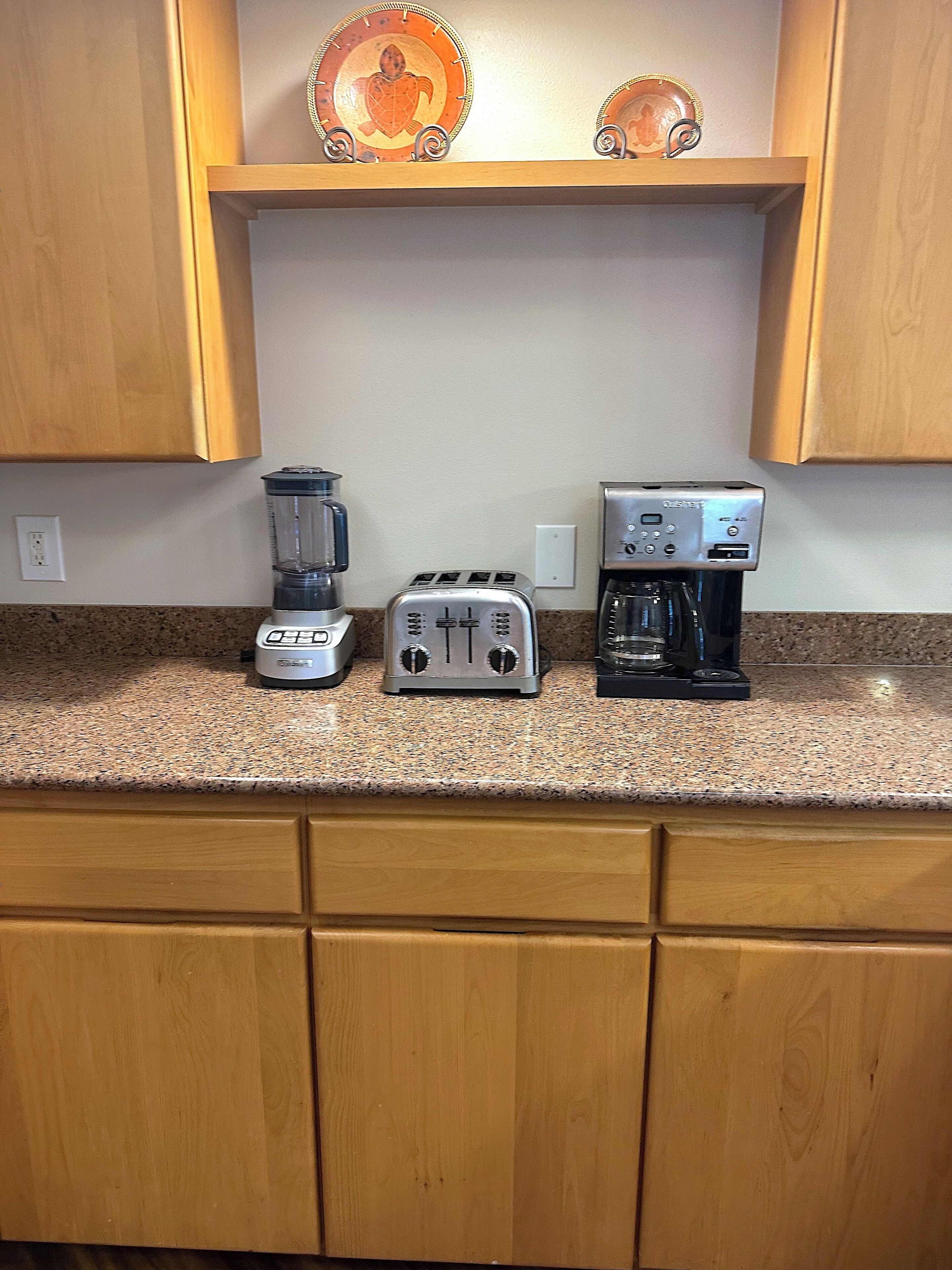 A kitchen with wooden cabinets, a granite countertop, a blender, a toaster, and a coffee maker.