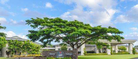 A welcoming sign for a clubhouse with a large tree in front.