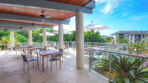 An outdoor patio with tables and chairs, umbrellas, and a pool area. - North Shore Beauty!  2B with Kitchen in Resort near Hanalei (Princeville)