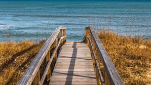 A wooden boardwalk leading to a body of water. - A Shore Cure | Panoramic Ocean Views (Kure Beach)