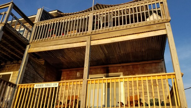 Ein mehrstöckiges Holzgebäude mit einem Balkon im Erdgeschoss.