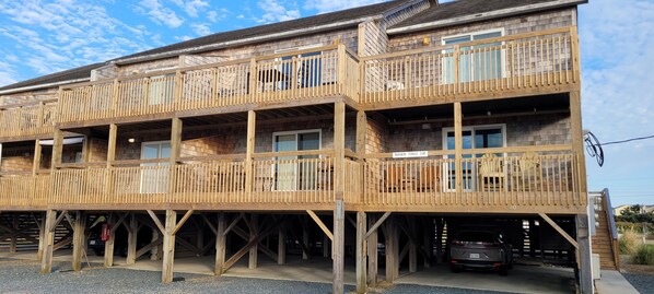 A multi-story wooden building with balconies and a garage. - Waterfront Condo. Amazing Sunsets over Pamlico Sound. Pool, Pickleball & Tennis! (Avon)