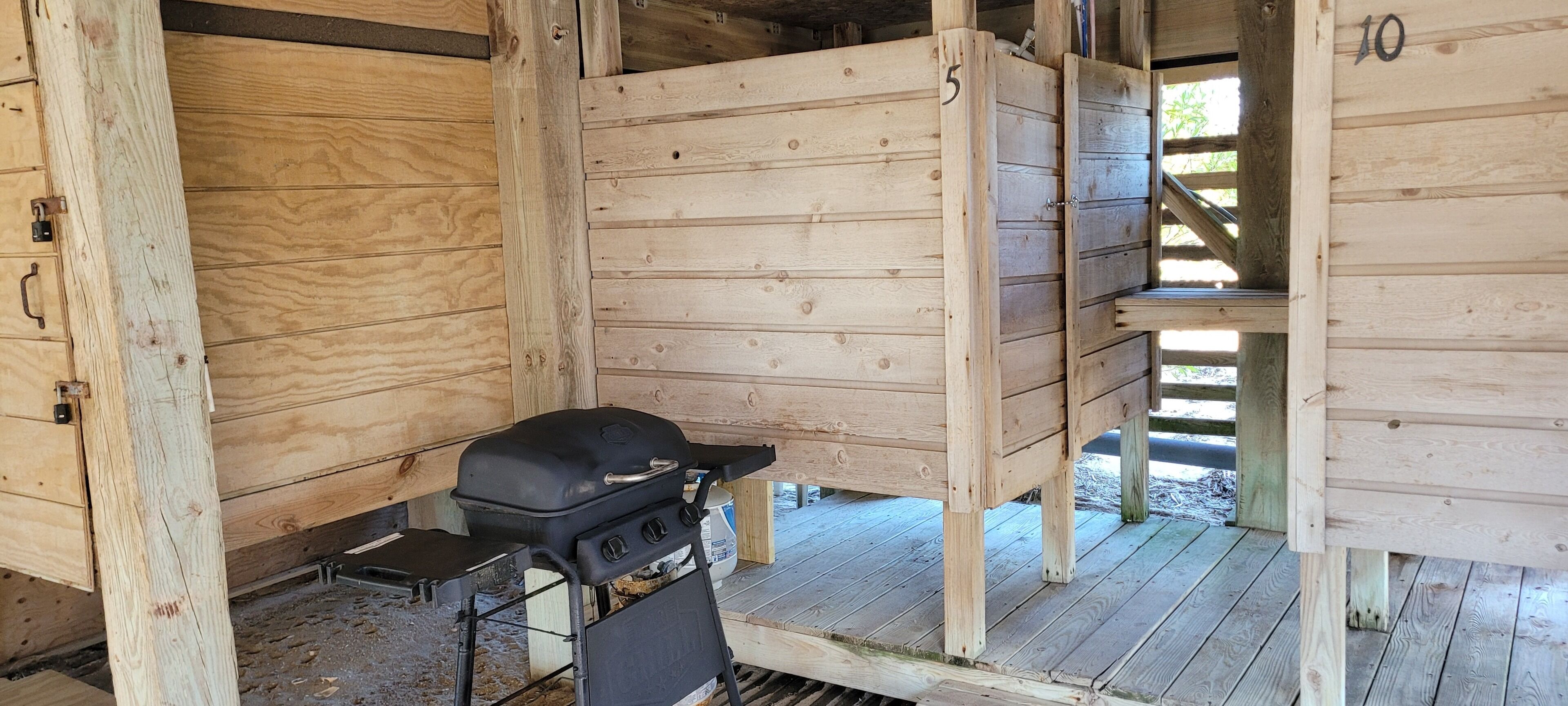 A wooden cabin with a grill and a small table.