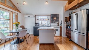 A modern kitchen with wooden floors, a central island, and a stainless steel refrigerator.
