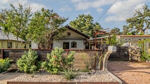 A house with a wooden deck, a stone mailbox, and a garden with various plants.