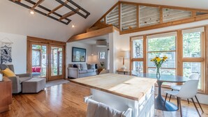 A spacious living area with a wooden ceiling, large windows, and a central island.