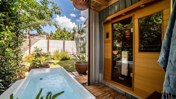 A spa area with a hot tub, wooden deck, and a glass door leading to a room.
