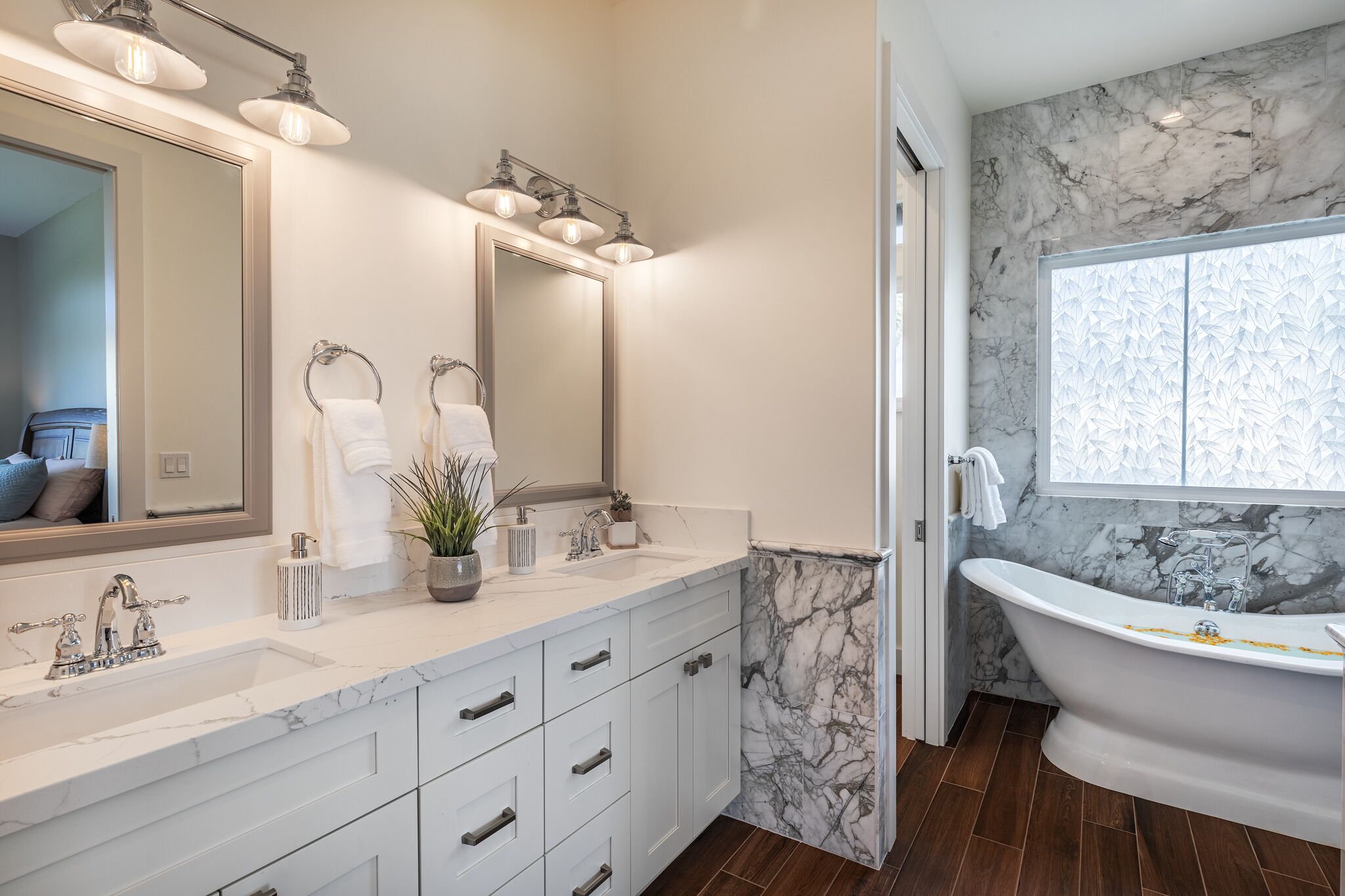 Un bagno moderno con un lavabo in marmo, una vasca da bagno indipendente e un grande specchio con illuminazione.