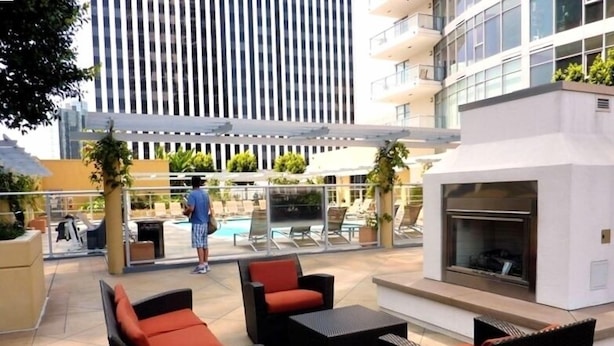 An outdoor lounge area with wicker furniture and a built-in fireplace. - WEST OCEAN TOWERS Long Bch Condo 2Bed/2BA/Sunny/Balcony/ Pool/Gym/BEST BUILDING! (Long Beach)