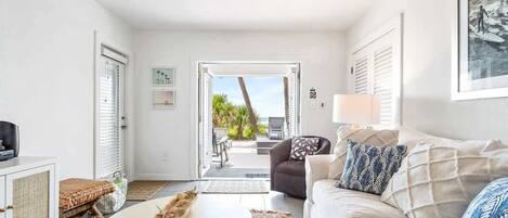 A living room with a sofa, a coffee table, a wicker basket, and a view of the outdoors.