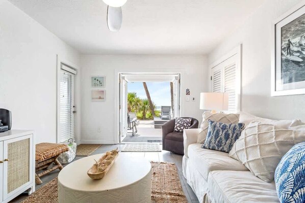 A living room with a sofa, a coffee table, a wicker basket, and a view of the outdoors.
