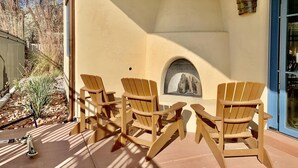 A patio area with three wooden Adirondack chairs, a small table, and a stone fireplace.
