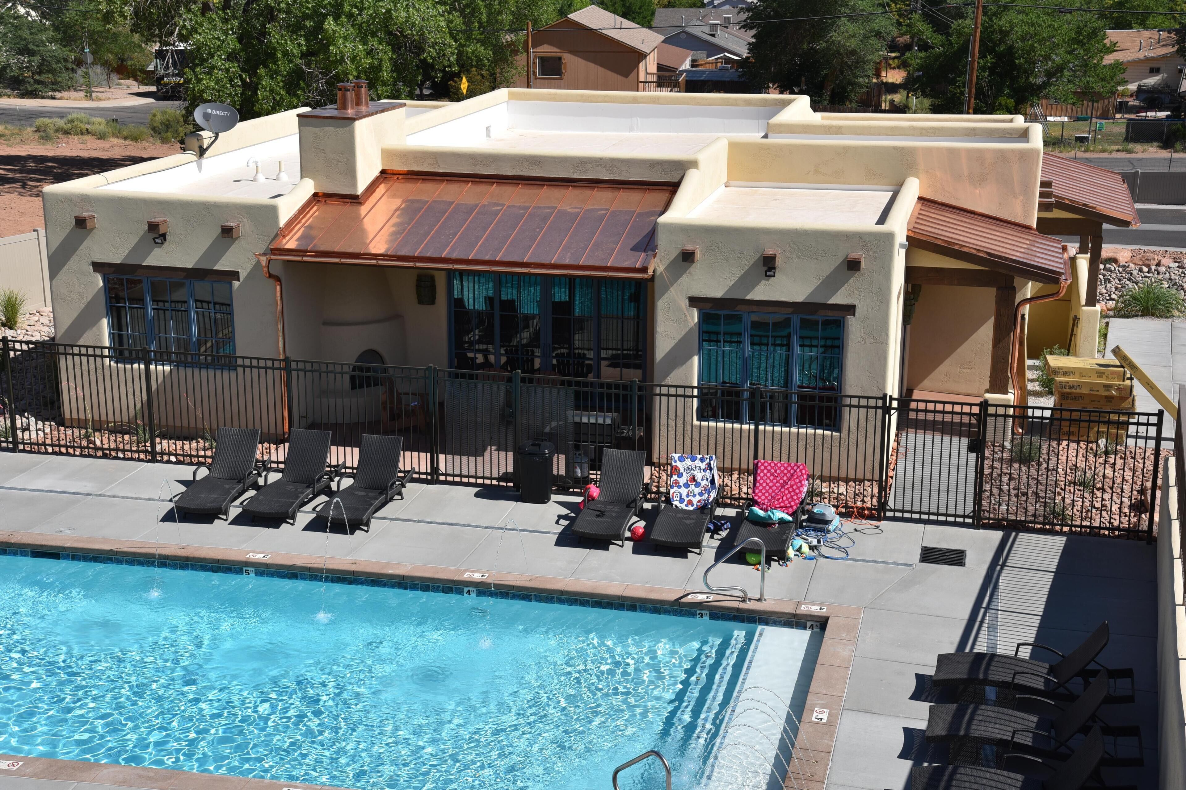 A pool area with lounge chairs and a building with a flat roof and windows.