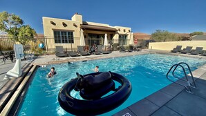 A swimming pool with lounge chairs and a building in the background.