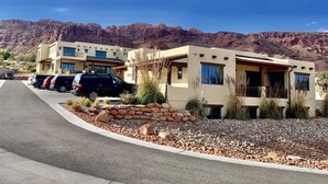A modern building with a parking area and a view of mountains.