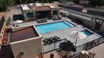 Un espace piscine aménagé sur le toit, avec des chaises longues, une piscine et un espace salon couvert.