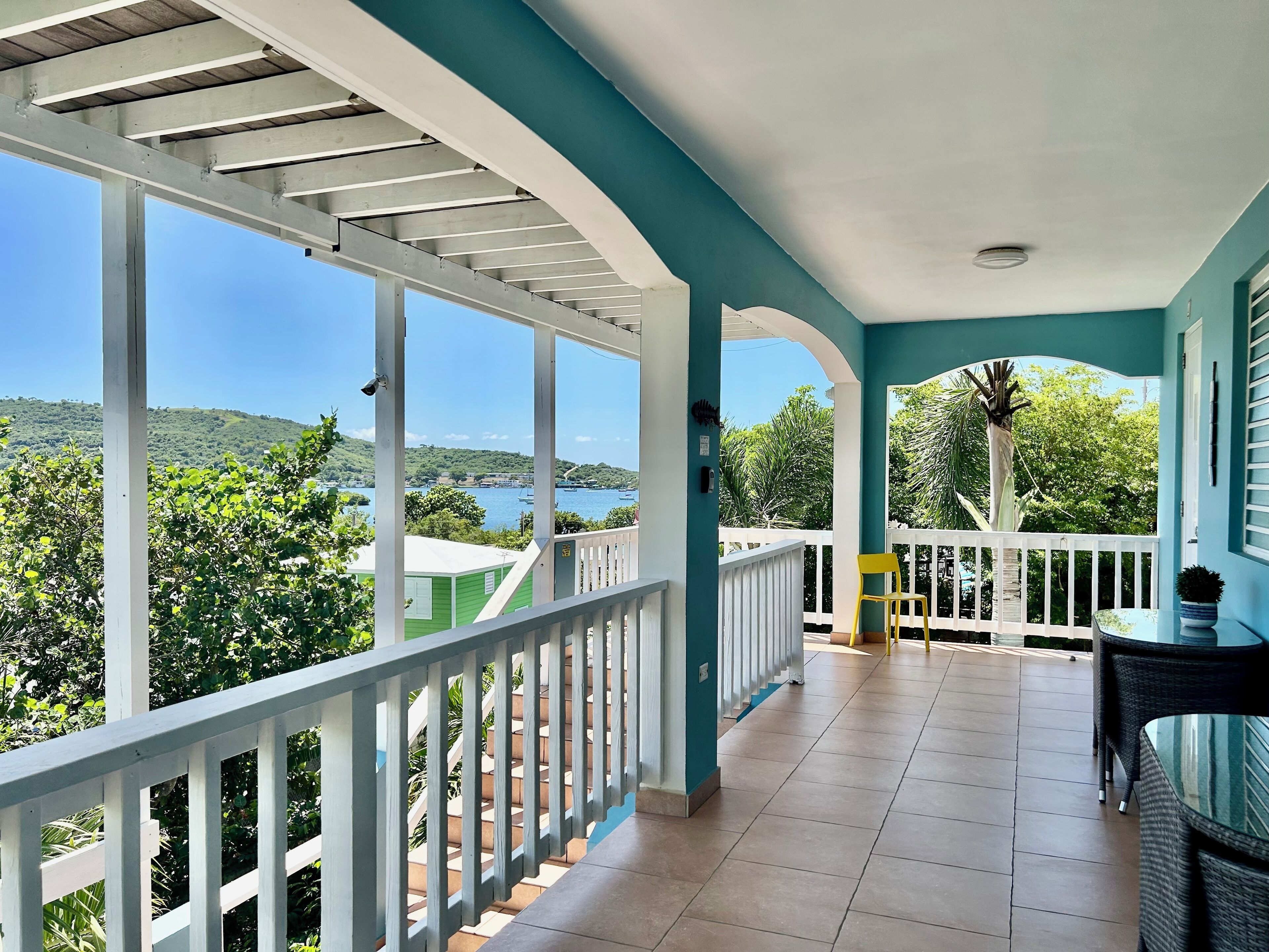 Un balcon fermé offrant une vue sur la mer et la verdure.