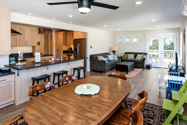 Una cocina amplia con armarios de madera, un comedor con una gran mesa de madera, y una sala de estar con sofá y sillones.