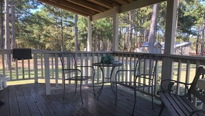A covered porch with wooden flooring, metal chairs, a small round table, and a bench. - Julia's Cottage, peace @ Music Springs (Hawkins)