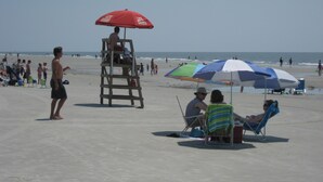 Een strand met een badwachterpost, strandstoelen en parasols.
