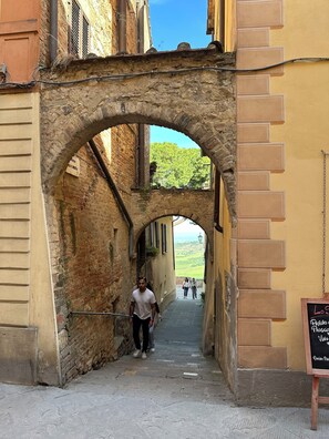 A narrow alleyway with an arched stone bridge, stone walls, and a signboard.