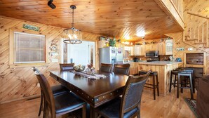 Un interior de madera con una mesa de comedor, sillas, una zona de cocina y una escalera.