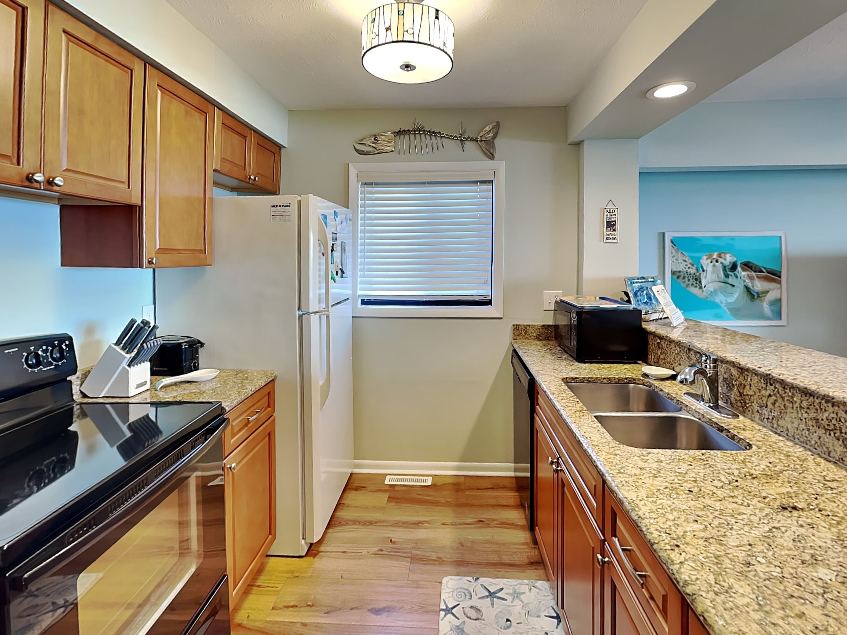 A kitchen with wooden cabinets, a refrigerator, a stove, a microwave, and a sink.