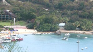 A coastal area with boats docked near a beach, surrounded by lush greenery and a few buildings. - String of Pearls Cozy Romantic Beach Front 1bedroom- Last Minute Discount! Ask! (Chocolate Hole)