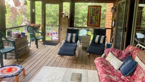 A covered porch with wooden flooring, two lounge chairs, a sofa, and a table. - Walking distance to all you will need! Sleeps 8-10 (Ellison Bay)