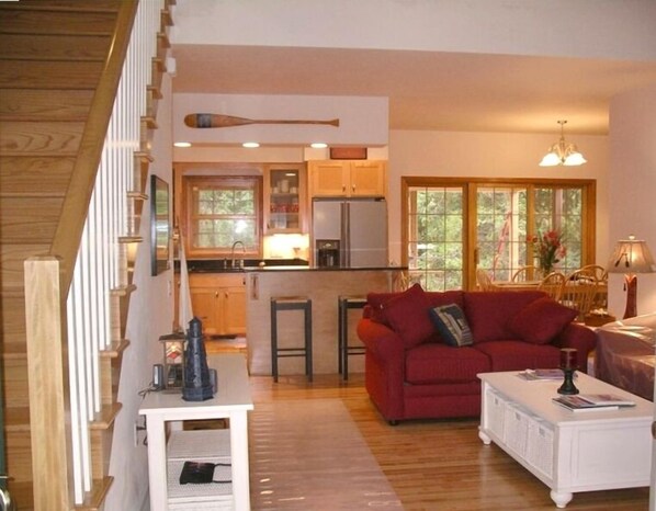 A spacious living area with a red sofa, a white coffee table, and a kitchen in the background.