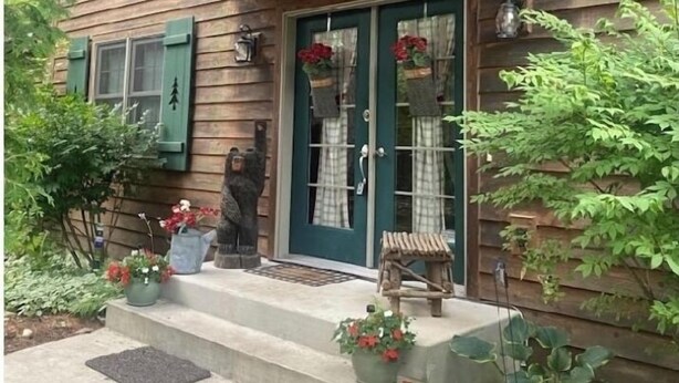 A wooden house with a porch, green shutters, and a small bench. - Walking distance to all you will need! Sleeps 8-10 (Ellison Bay)