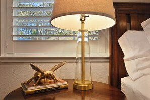 A table lamp with a clear glass shade and a gold base, placed on a wooden table next to a stack of books. - Close to Sonoma Plaza, Hot Tub and Bikes Included (Sonoma)