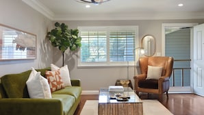 A living room with a green sofa, a brown leather chair, a glass coffee table, and a large plant. - Close to Sonoma Plaza, Hot Tub and Bikes Included (Sonoma)