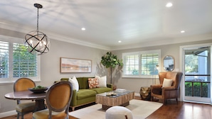 A living room with a green sofa, a wooden coffee table, and a dining table with chairs. - Close to Sonoma Plaza, Hot Tub and Bikes Included (Sonoma)