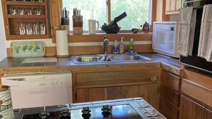 Una cocina con estufa, lavamanos y ventana.