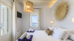 Une chambre à coucher comprenant un lit, une fenêtre, un téléviseur fixé au mur et un élément décoratif mural.