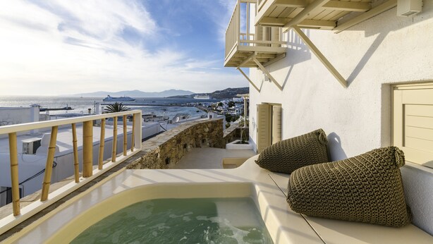 Un balcon avec vue sur la mer, un jacuzzi et deux coussins à texture particulière.
