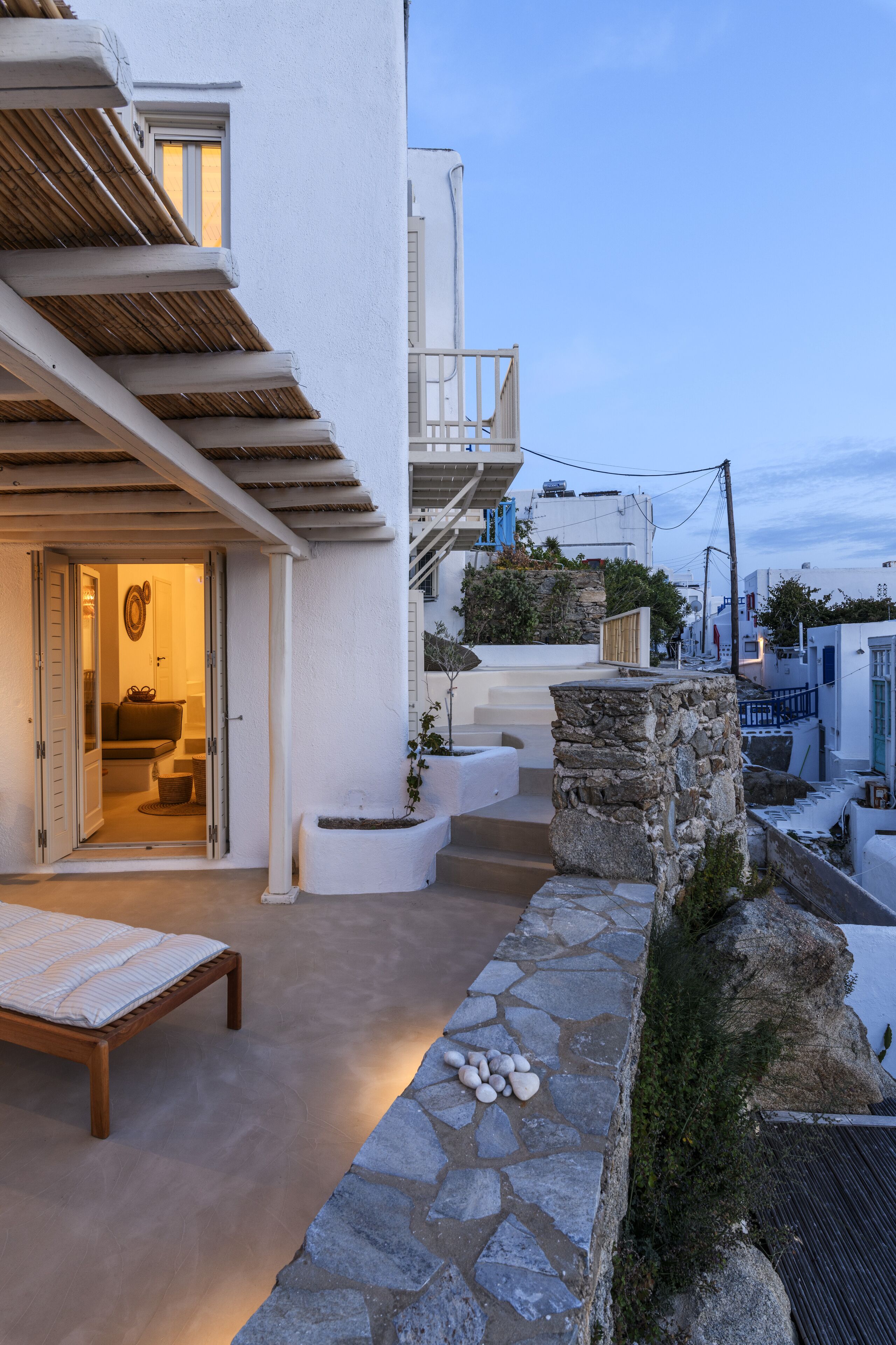 A modern outdoor seating area with a stone bench, a stone planter, and a stone wall.