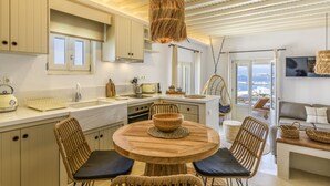 Une cuisine moderne avec une table ronde en bois, des chaises en osier et un luminaire suspendu.