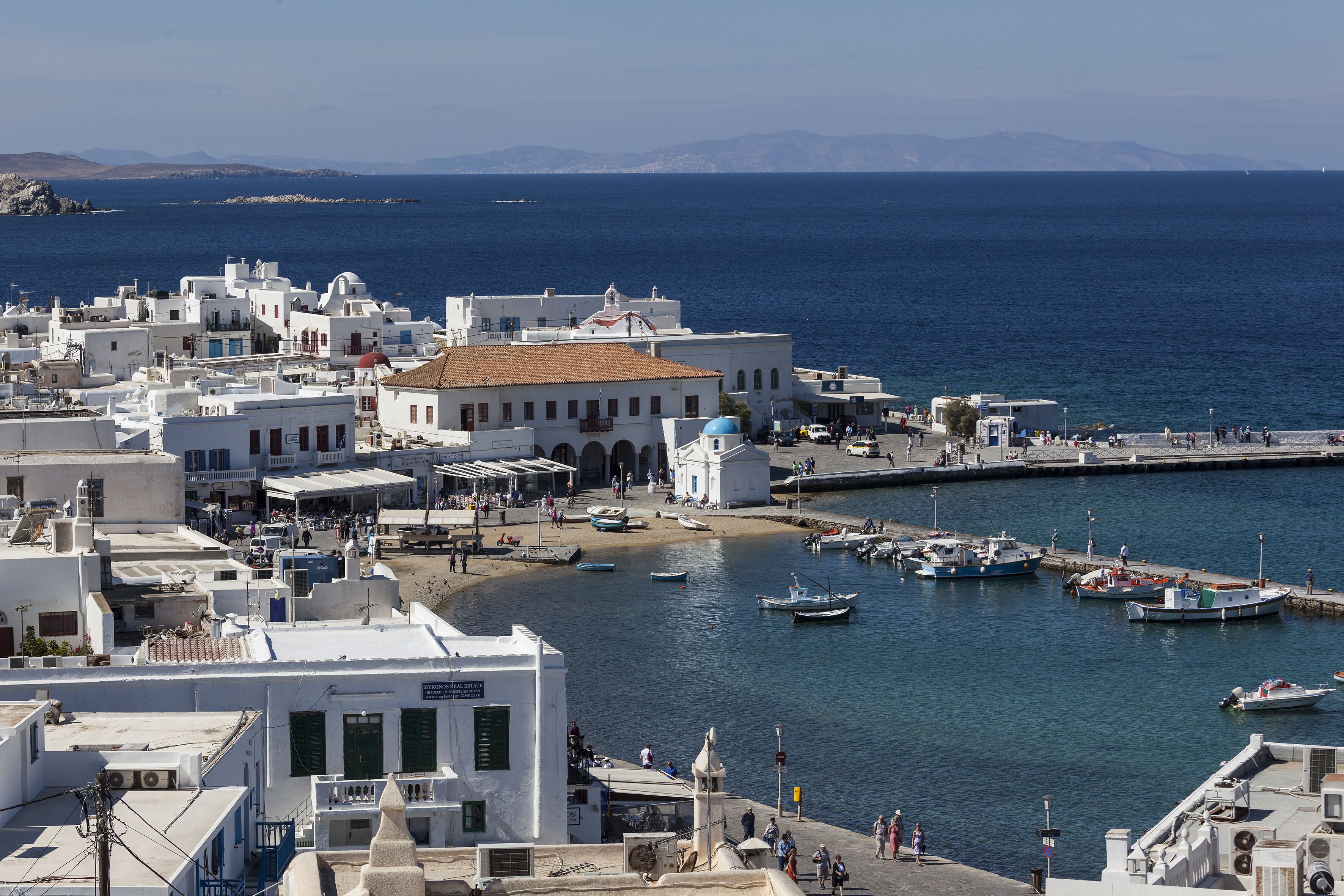 Un pueblo costero con edificios blancos, un puerto deportivo y barcos.