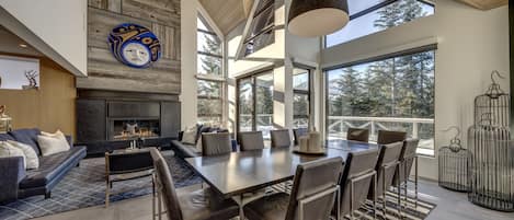 A spacious living area with a fireplace, a large dining table, and a view of the outdoors.