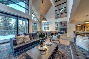 A spacious living area with a large sofa, a coffee table, and a dining area with chairs. - This is the largest ski in ski out rental townhome in Whistler. And it's swanky. (Whistler)